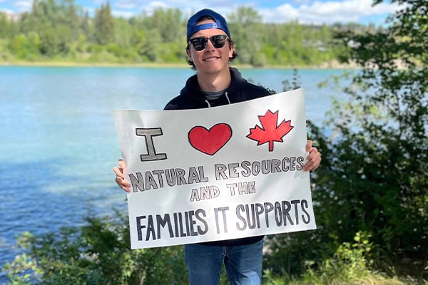 Young Canadian supporter holding a natural resources advocacy sign outdoors at YCR event.