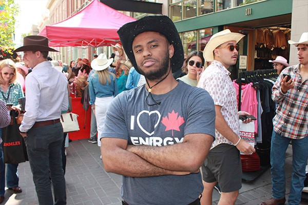 Youth man wearing cowboy hat at outdoor event supporting Canadian energy resources.