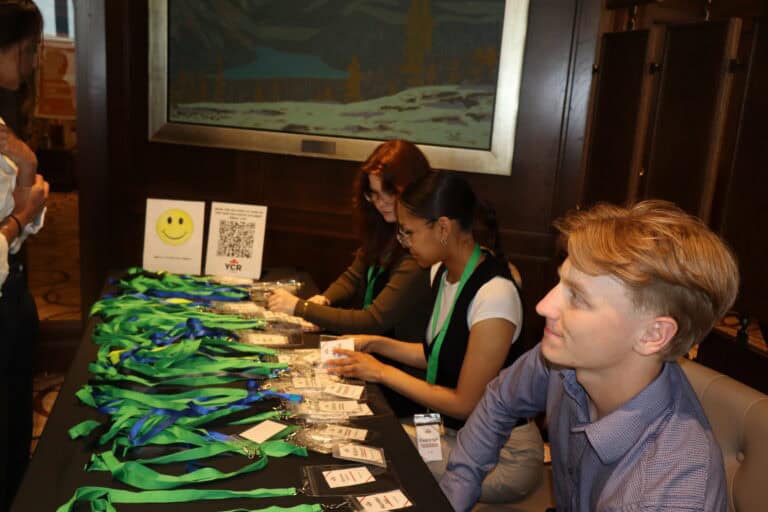 Young professionals registering at a conference table with lanyards and badges, engaging in networking and event check-in.