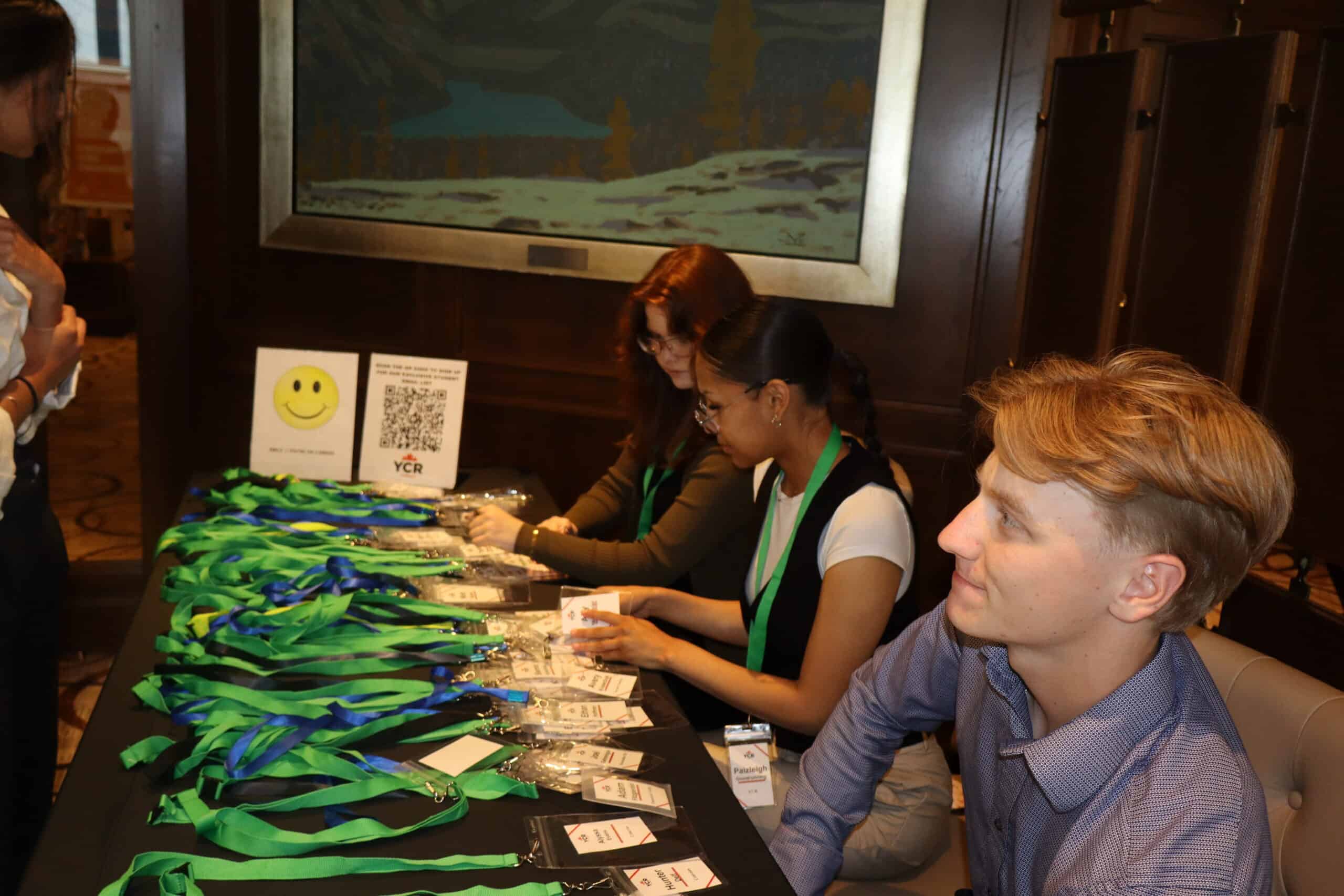 Young professionals registering at a conference table with lanyards and badges, engaging in networking and event check-in.